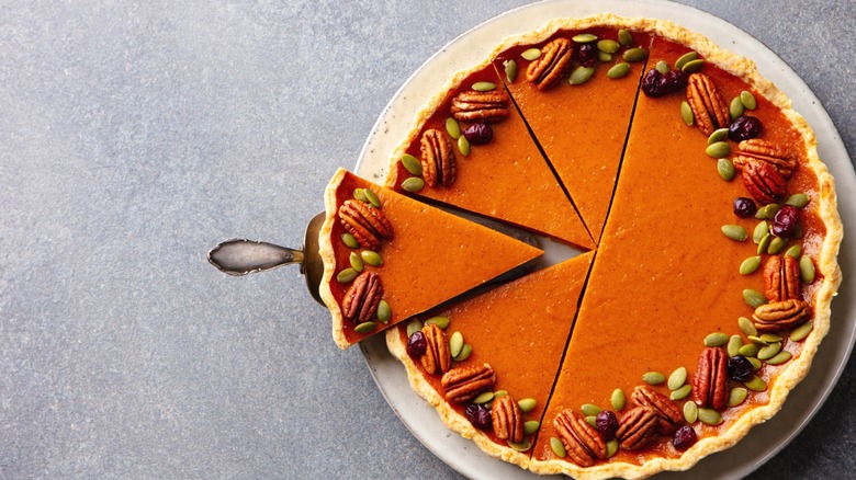 A pumpkin pie with a slice taken out of it.