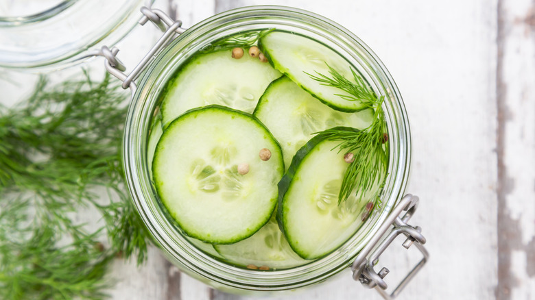Top view of sliced cucumber pickles with coriander seeds and fresh dill