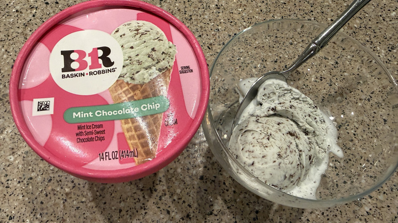 Baskin Robbins pint of Mint Chocolate Chip with a scoop in a glass bowl with a spoon