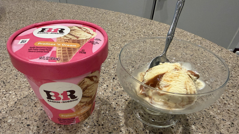 Baskin Robbins pint of Pralines n' Cream with a scoop in a glass bowl with a spoon