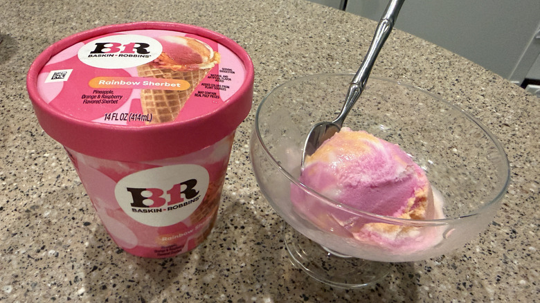 Baskin Robbins pint of Rainbow Sherbet with a scoop in a glass bowl with a spoon