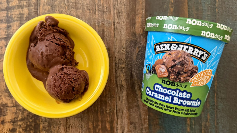 Two scoops of Ben & Jerry's Chocolate Caramel Brownie non-dairy ice cream next to a pint