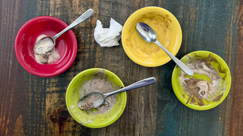 empty ice cream bowls, crumpled napkin, and used spoons on a table