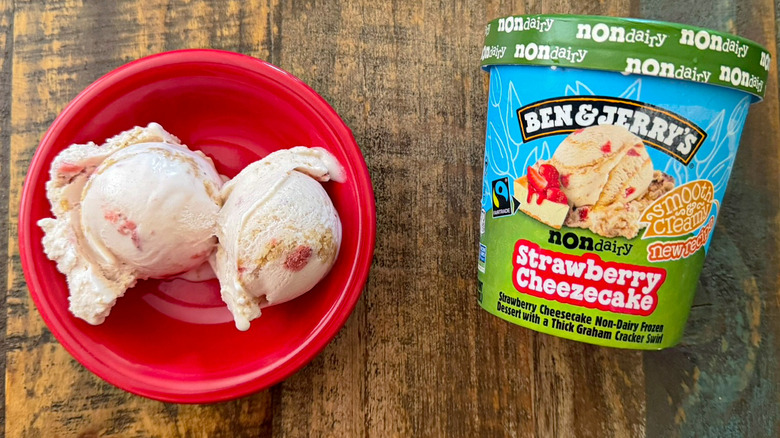 Two scoops of Ben & Jerry's Strawberry Cheezecake non-dairy ice cream next to a pint