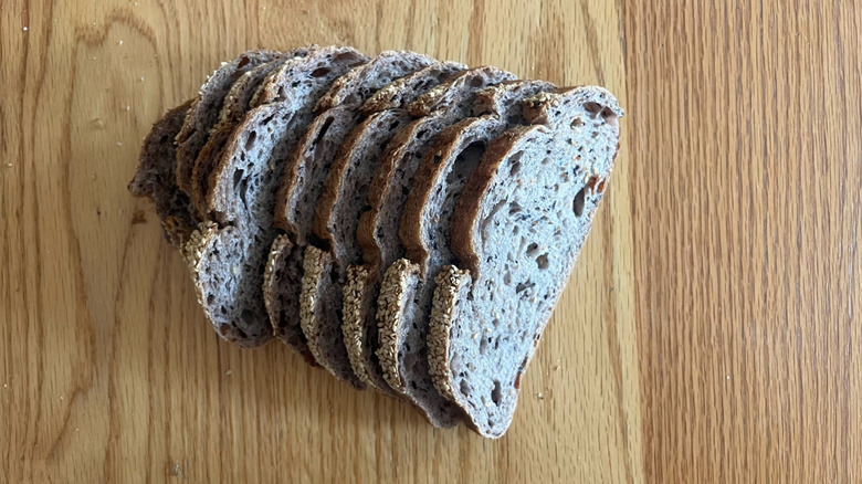 A sliced loaf of forbidden rice bread sits on a wooden counter