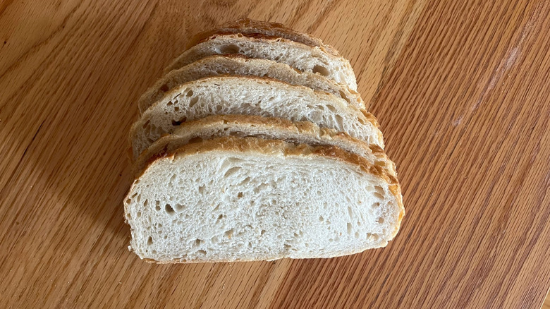 A loaf of sourdough sits on a wooden counter