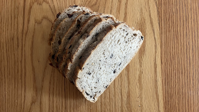 A slice of bread is flecked with olives