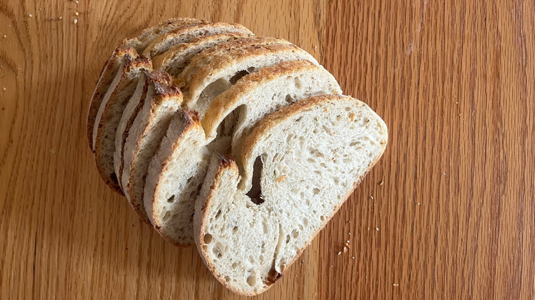 A loaf of rosemary sourdough sits on a wooden counter