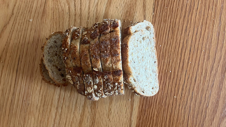 A loaf of bread is arranged in slices on a wooden counter