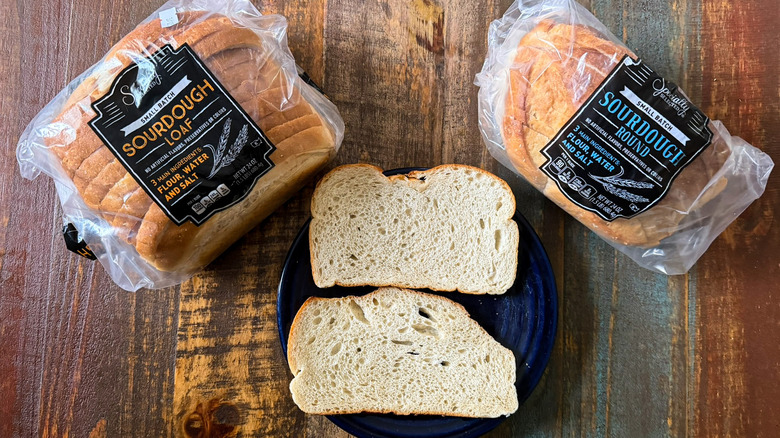 Packages of Aldi Specially Selected Sourdough Loaf and Sourdough Round flanking a plate with two slices of bread