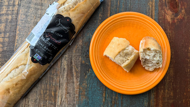 Aldi Specially Selected French Baguette in its packaging next to a plate with two torn pieces of bread