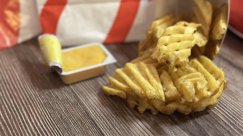 Medium Chick-fil-A Waffle Potato Fries on a wooden placemat with Chick-fil-A sauce on the side