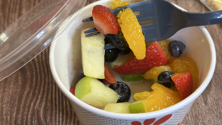 Chick-fil-A Fruit Cup including pieces of orange, strawberry, apple, and blueberries with a fork