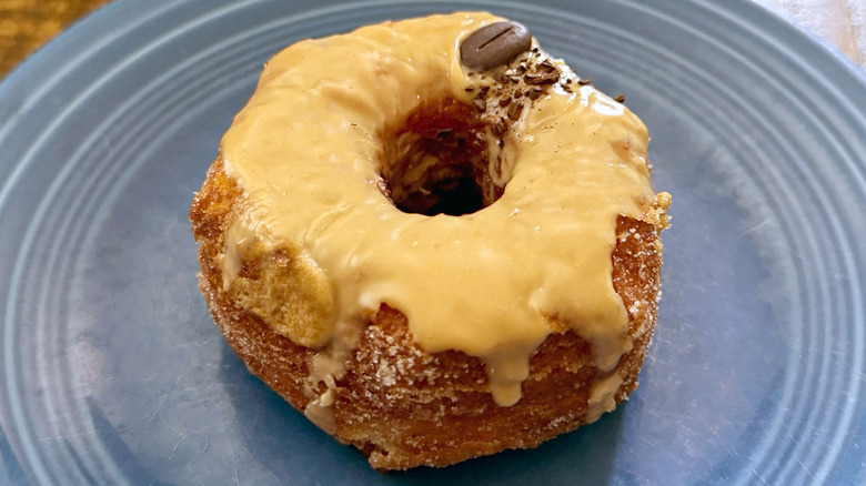 A coffee croissant donut from Paris Baguette with coffee glaze and coffee bean on plate