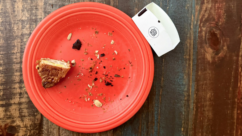 Paris Baguette Croissant crumbs on a plate next to bakery paper takeout tray