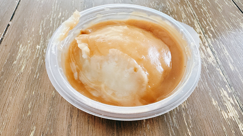 KFC Mashed Potatoes and Gravy in plastic container on wooden table