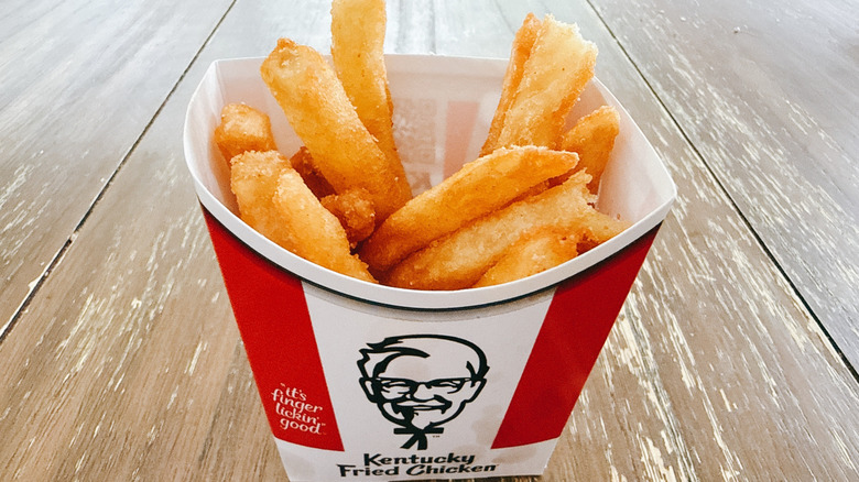KFC secret recipe fries in paper cup on wooden table