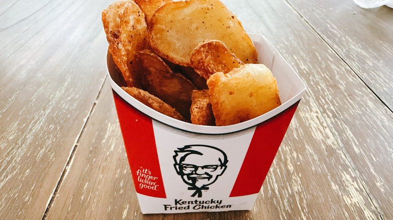 KFC potato wedges in paper cup on wooden table