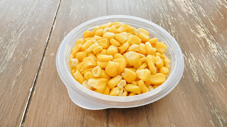 KFC corn in plastic packaging on wooden table