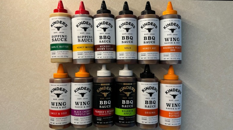 12 Kinder's sauce bottles on a beige surface