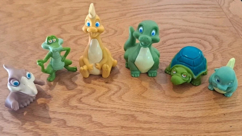 Six colorful plastic toys shaped like dinosaurs and other reptiles