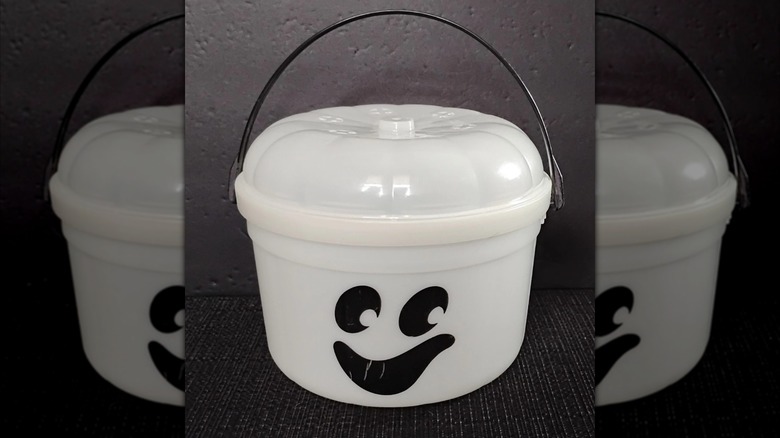 A white Halloween bucket for trick or treating, decorated with a ghostly face
