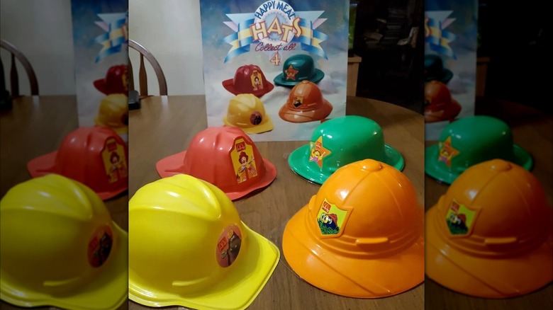 Four plastic hard hats in various bright colors on a wooden surface