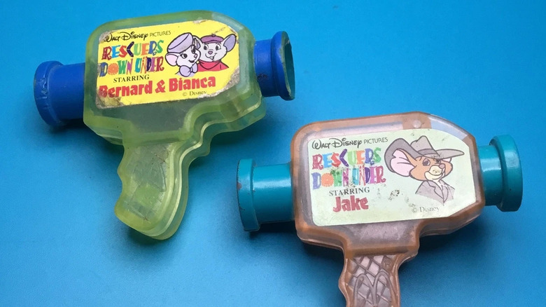 Two small, brightly colored toys shaped like camcorders and decorated with Rescuers Down Under branding