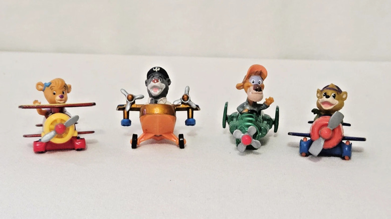 Four colorful toys shaped like planes manned by animals, on a white background