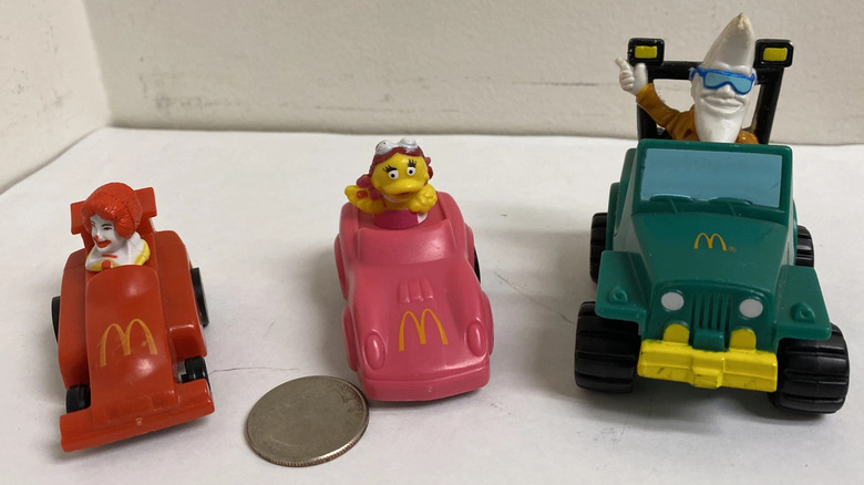 Three plastic toy cars on a wooden table