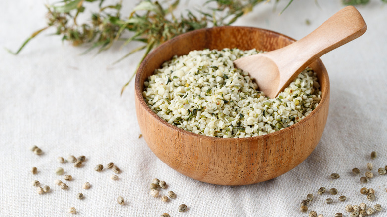 Shelled hemp seeds inside a wooden bowl with a spoon