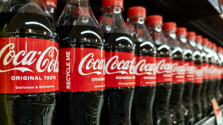 Several bottles of Coca-Cola on a store shelf