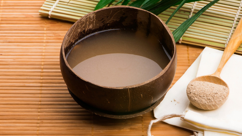 A wooden bowl of awa with a spoon of powder