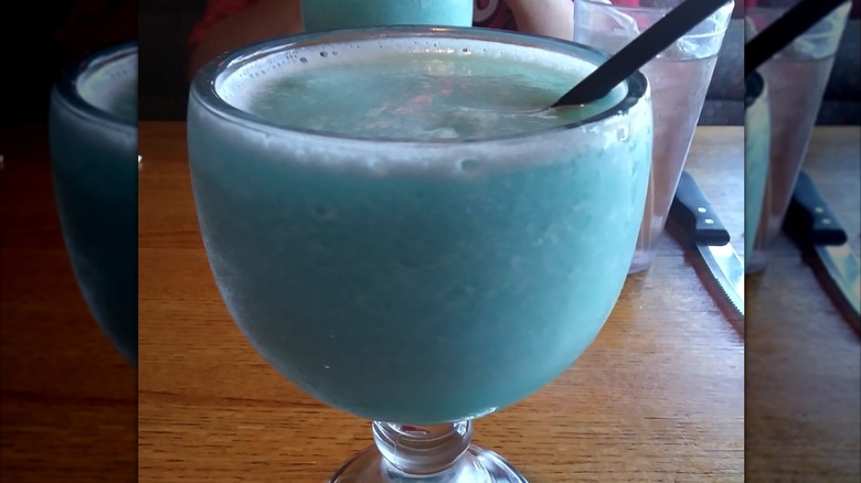 A glass of frozen blue water margarita on a restaurant table