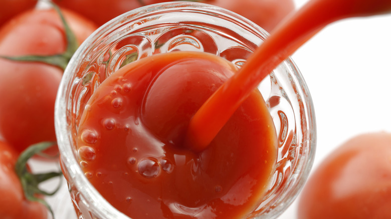 A glass of tomato juice being poured