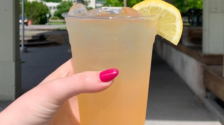 A hand holding cup of maple lemonade