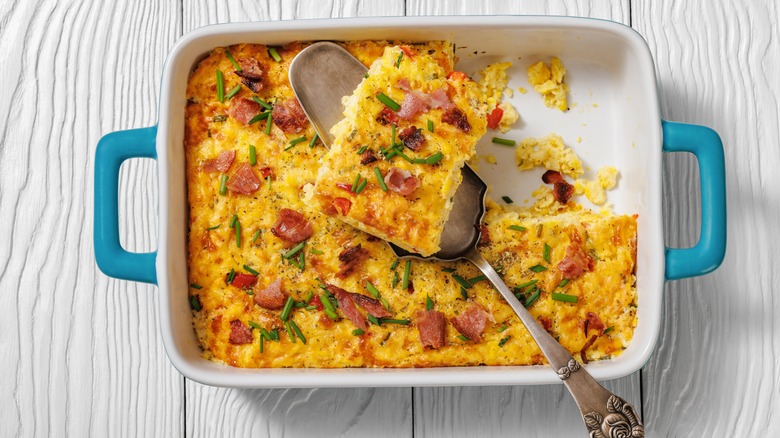 Corn and bacon casserole in dish with spoon