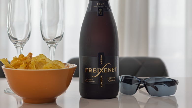 Bottle of Freixenet cava with chips, glasses, sunglasses