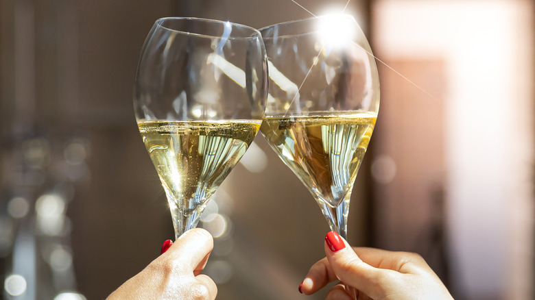 Two hands toasting glasses of sparkling white wine