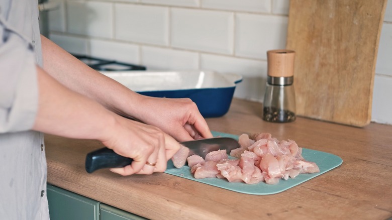 Woman cutting raw chicken in a kitchen