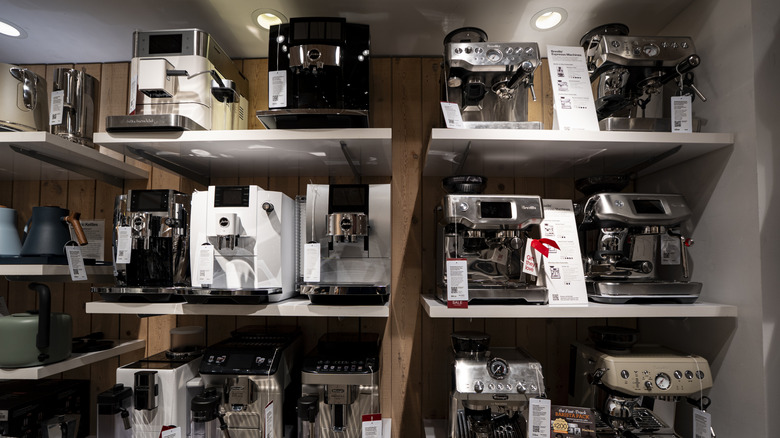De'Longhi, Nespresso, Breville, and Jura coffee machines on shelves for sale at a store
