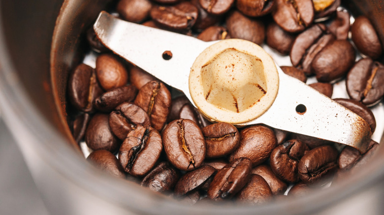 Close-up of roasted coffee inside metal electric grinder.
