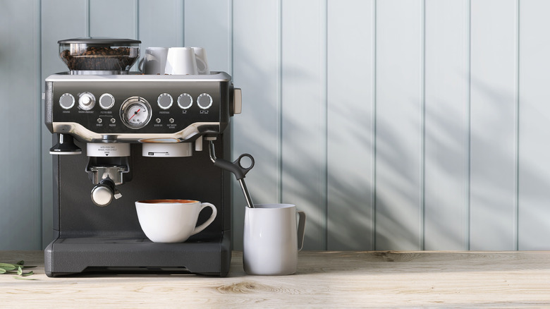 Close up of modern and luxury black espresso maker on wooden counter with milk steam and coffee cups