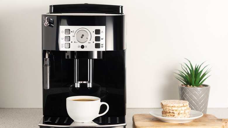Modern espresso coffee machine with a cup in interior of kitchen closeup.