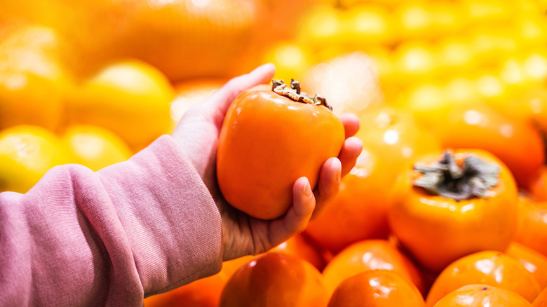 Person holding a persimmon in a store