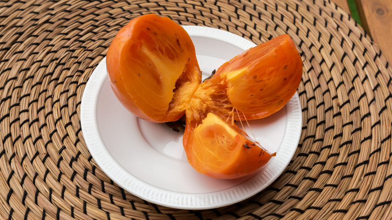 A persimmon cut into pieces on a plate