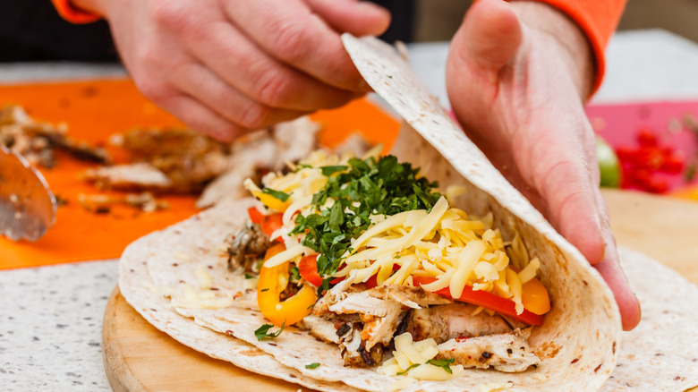 A chef folds ingredients into a flour tortilla