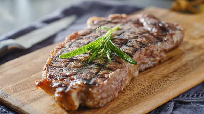 Grilled New York Strip on cutting board with rosemary