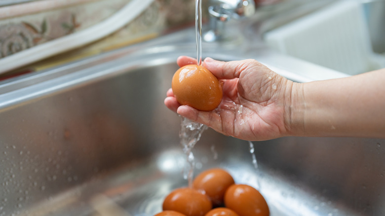 Someone washing an egg in the sink