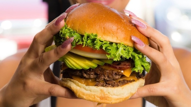hands holding burger with vegetables and cheese from Burger Boss